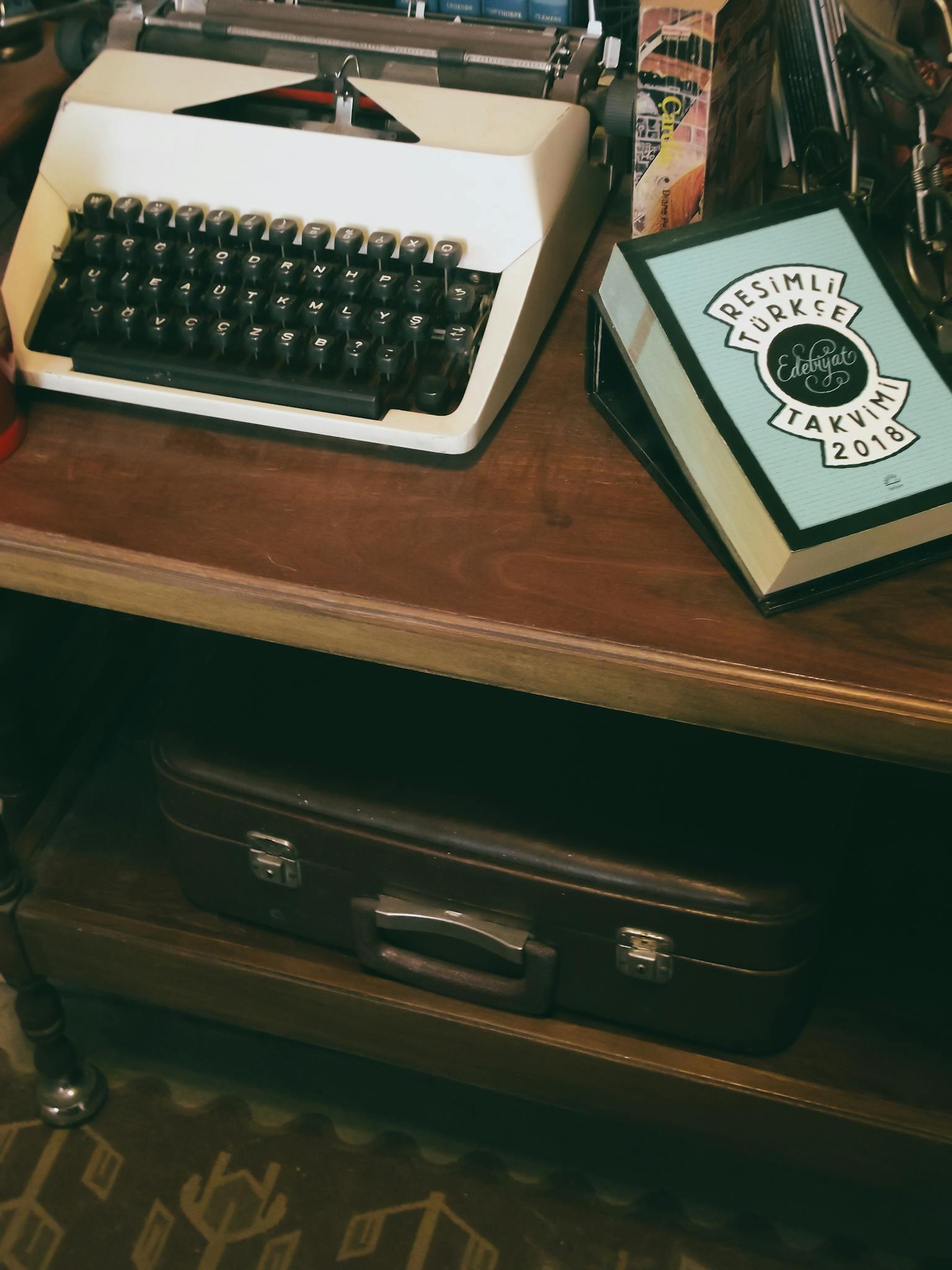 A nostalgic scene featuring a vintage typewriter on a wooden desk with a book labeled in Turkish.
